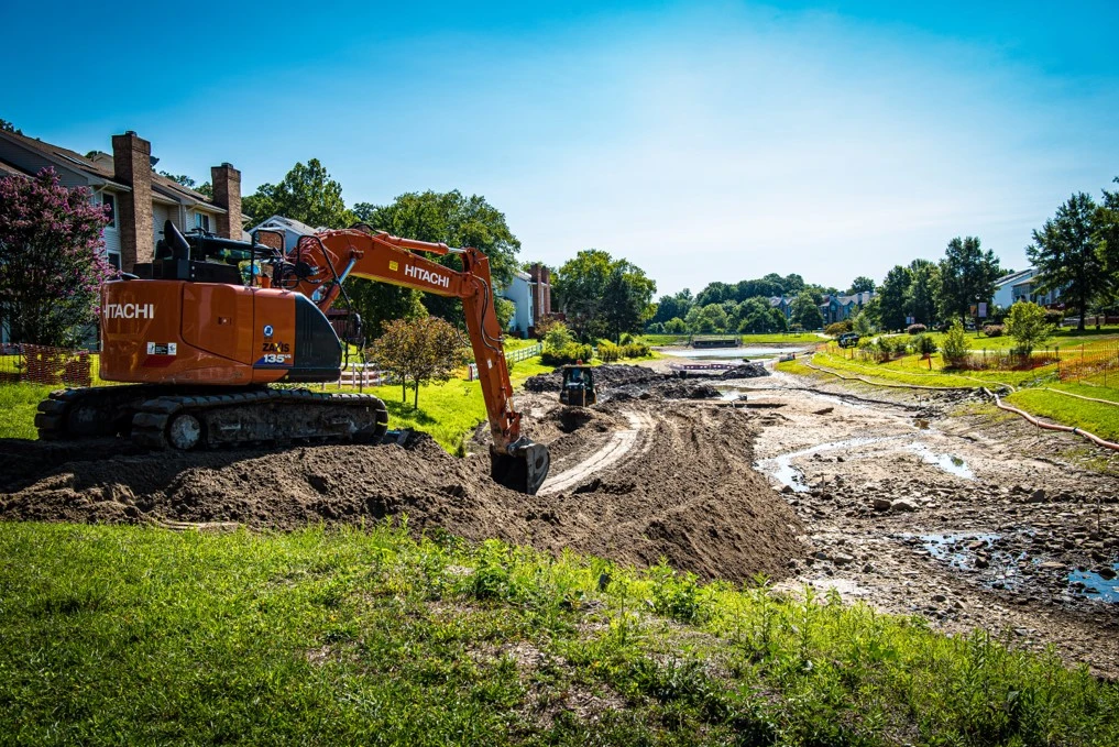 An excavator, a site development and earthwork contractor, is working on a dirt road.