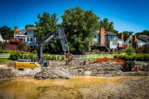 An excavation contractor is digging up a pond in front of a house for stormwater management.