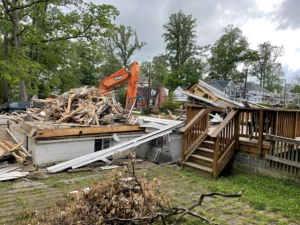 A house is being demolished by an excavation contractor in the middle of a yard.