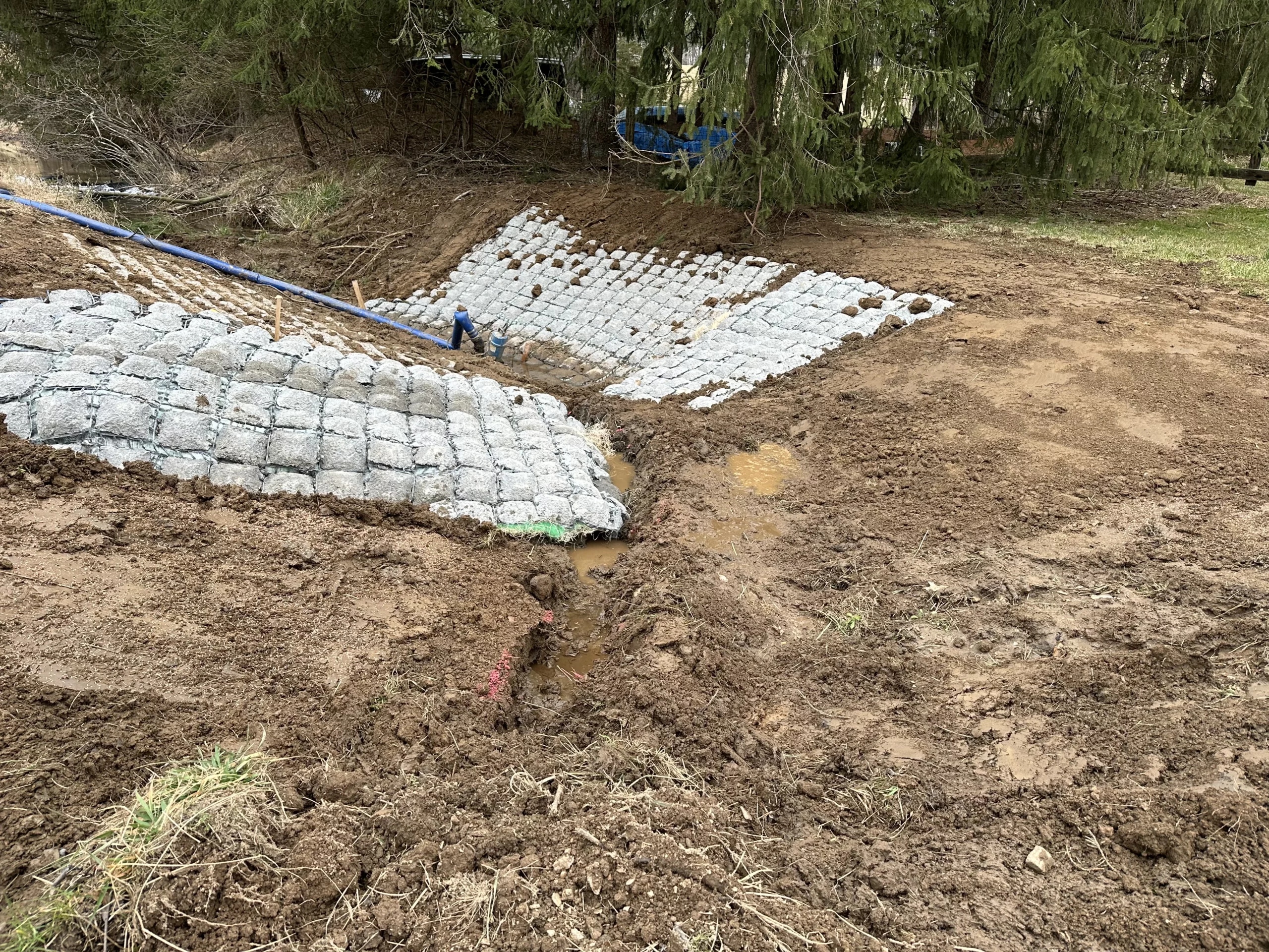 An earthwork contractor is constructing a sand berm in a yard.