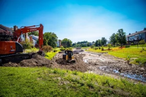 An excavation contractor is performing site development work on a dirt road, including stormwater management.